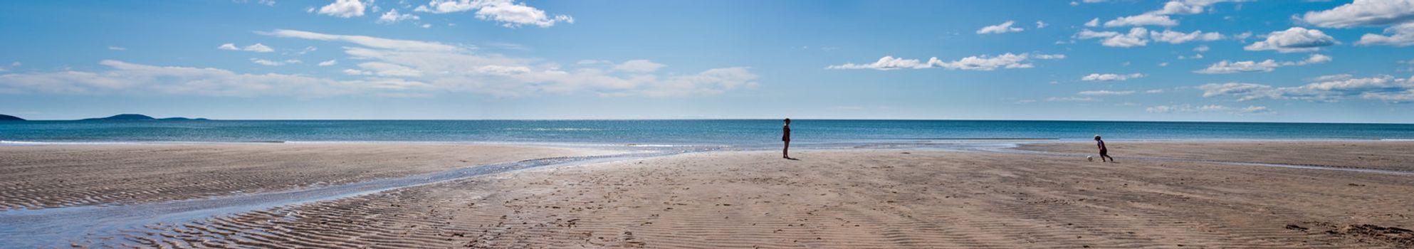 Panoramic photo of a mother and son playing on the beach