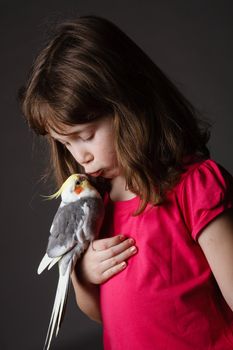 Cute little girl with a pet cockatiel in her hand