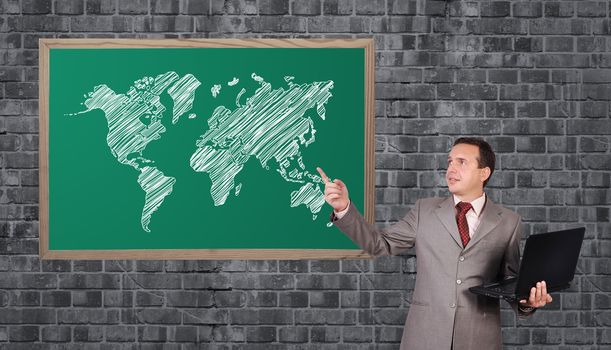 businessman with a laptop in hand points to word map on blackboard