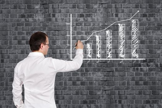 businessman drawing business chart on brick wall