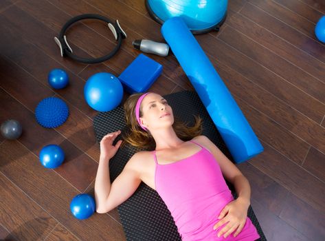 Aerobics instructor woman tired resting lying on mat with pilates balls and bands