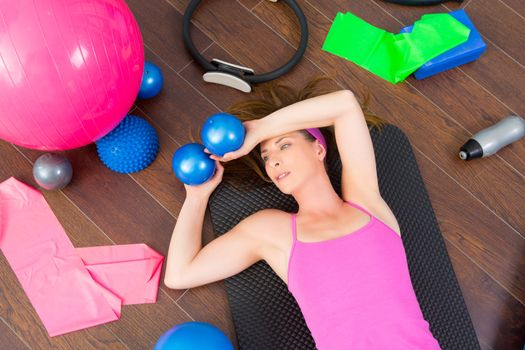 Aerobics instructor woman tired resting lying on mat with pilates balls and bands