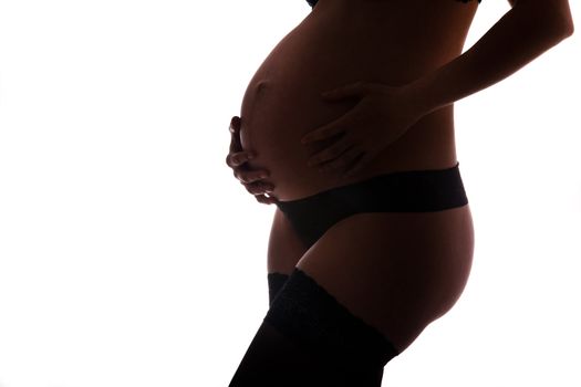 Pregnant woman wearing lingerie holding her belly 