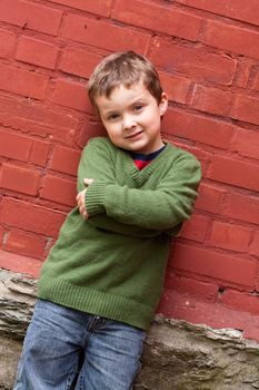 Cute little boy standing in front of a brick wall