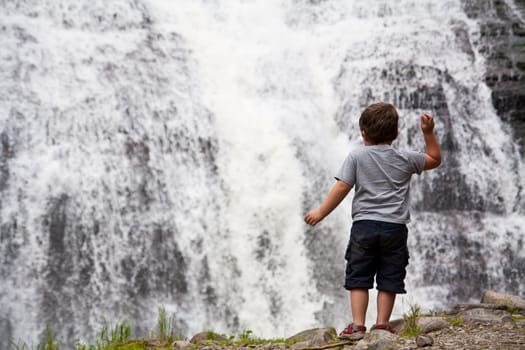 Little boy throwing rocks in a waterfall