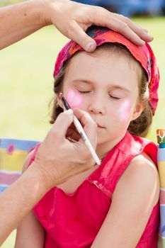 Cute little girl getting make-up on her face