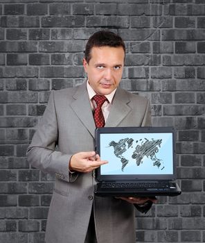 man with a laptop in hand points to world map on screen