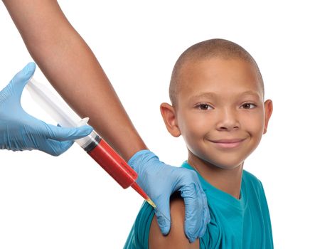 This smiling young boy receives a shot from a large syringe into his right arm.