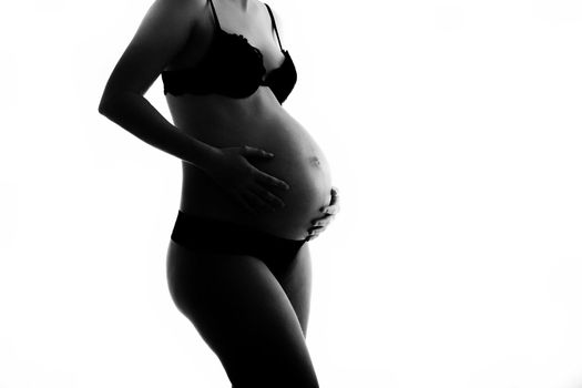 Pregnant woman wearing lingerie holding her belly