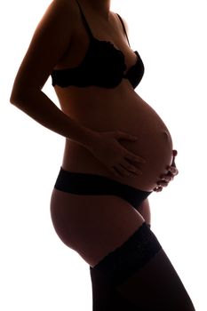 Pregnant woman wearing lingerie holding her belly