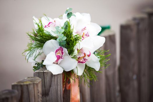 Wedding bouquet with white orchids on rustic country fence