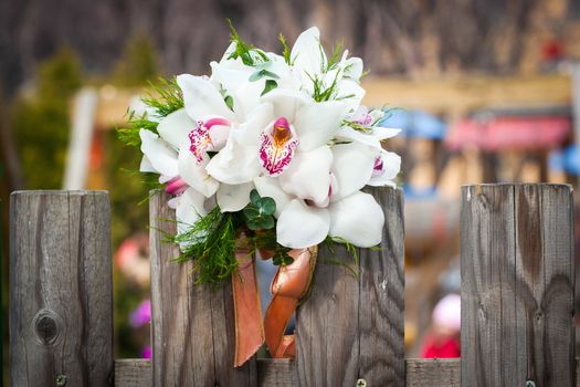 Wedding bouquet with white orchids on rustic country fence