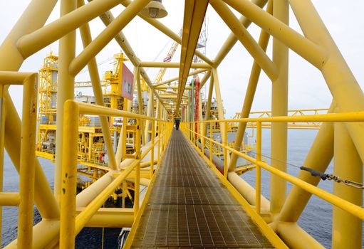 the worker is walking cross the pathway bridge of offshore oil rig