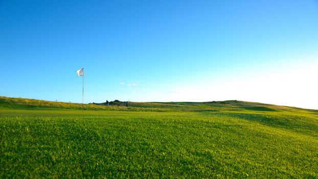 The flag is on the nice green golf course .