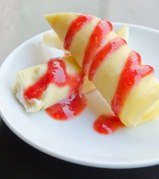 crepe rolls filled  with white cream , topping with strawberry  syrup