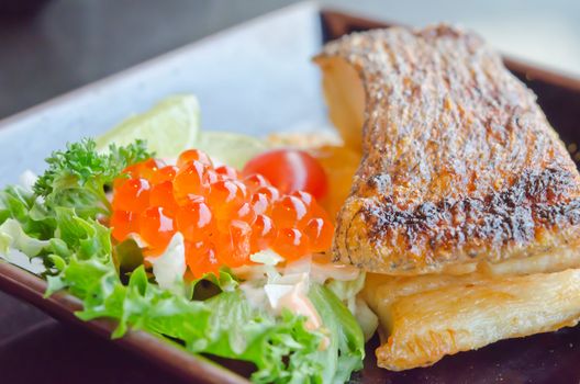 grilled cod fish  served with fresh salad with fish egg  on plate