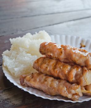 close up grilled pork  and  sticky rice on paper plate