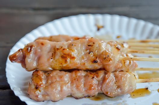 close up grilled pork  on white paper plate
