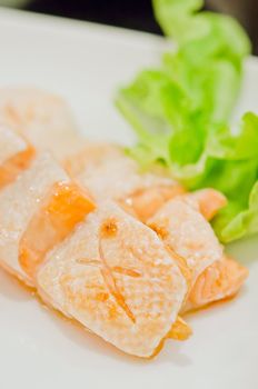 Grilled salmon belly served with fresh lettuce on dish