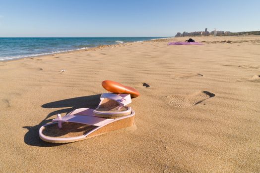 Sandals and sunscreen on a sunny sand beach