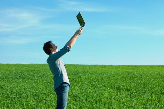 man with laptop standing in a field