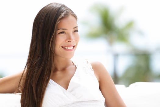 Asian woman casual confident looking to the side sitting outside relaxing. Fresh outdoor portrait of mixed race Asian Caucasian attractive brunette woman.