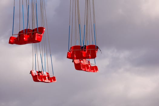 Red Carousel seats on cloudy sky