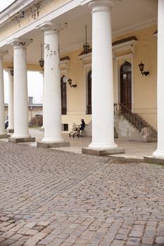Woman with baby carriage next to a colonnade in Odessa