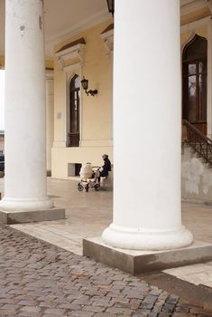Woman with baby carriage next to a colonnade in Odessa
