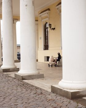 Woman with baby carriage next to a colonnade in Odessa