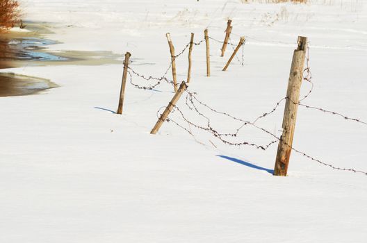 Barbed wire on a fence in the winter in the meadow