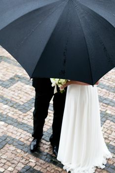 the bride and groom with a bouquet of flowers under the umbrella