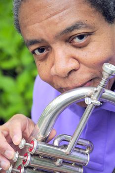 African American male with his flugelhorn outdoors.