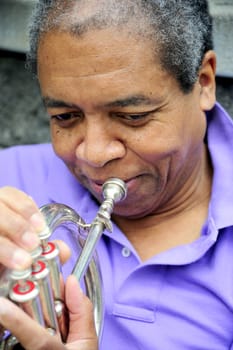 African American male with his flugelhorn outdoors.