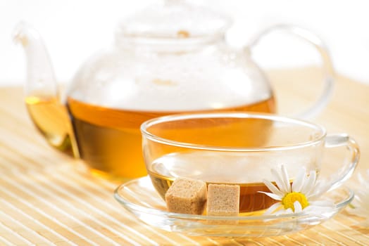 A teacup and a teapot with herbal chamomile tea