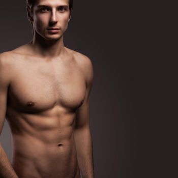 Handsome young man with naked torso on a grey background