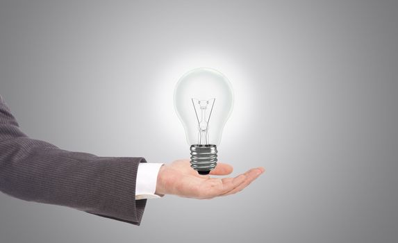 business man with light bulb in hand, grey background