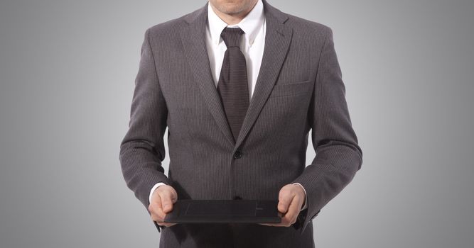 business man with touch tablet in hands, grey background. 