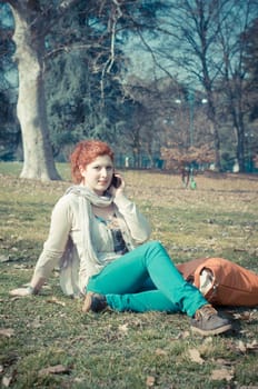 red long hair girl at the park on the phone in spring 