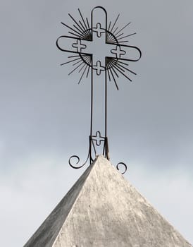 An ornate metal cross on the top of a steeple on a Catholic Church in Cotacachi, Ecuador