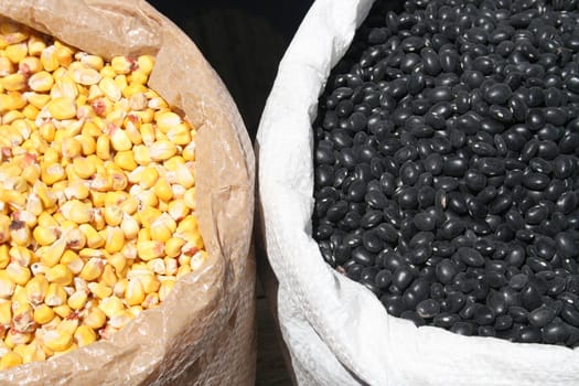 Sacks of black beans and yellow corn for sale at the outdoor food market in Cotacachi, Ecuador