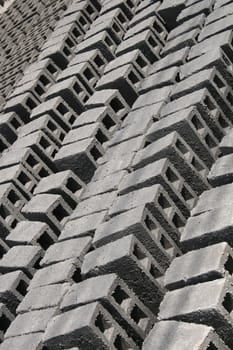 Rows of gray concrete bricks drying in the sun at an outdoor brickyard in Cotacachi, Ecuador