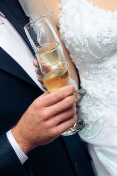 Glasses with wine in hands of wedding pair