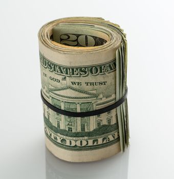 Roll of many $20 dollar bills and notes secured by elastic band on white table