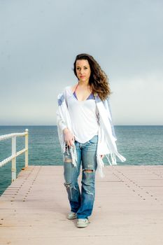 Beautiful teenager girl fashion shot on a peer, next to the sea.