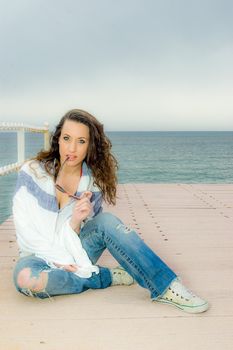 Beautiful teenager girl fashion portrait on a peer, next to the sea.
