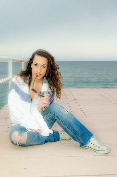 Beautiful teenager girl fashion portrait on a peer, next to the sea.