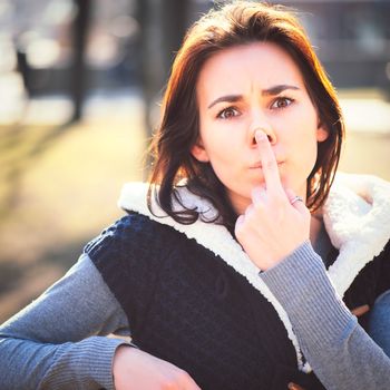 Portrait of young girl sitting on a bench in spring park in sunny day