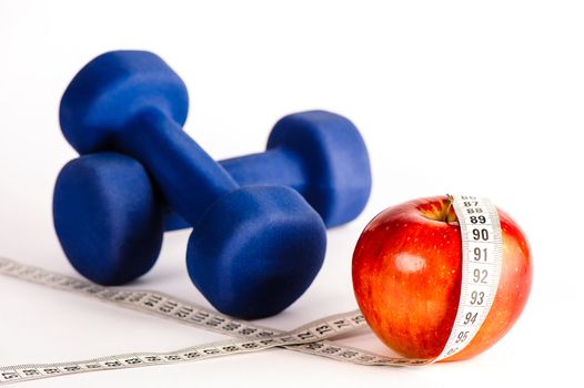 Blue dumbbells and red apple with measure tape isolated on a white background