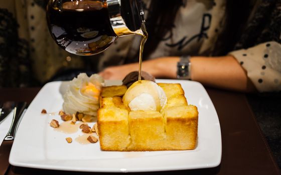 syrup being poured over a scoop of vanilla ice cream on toast